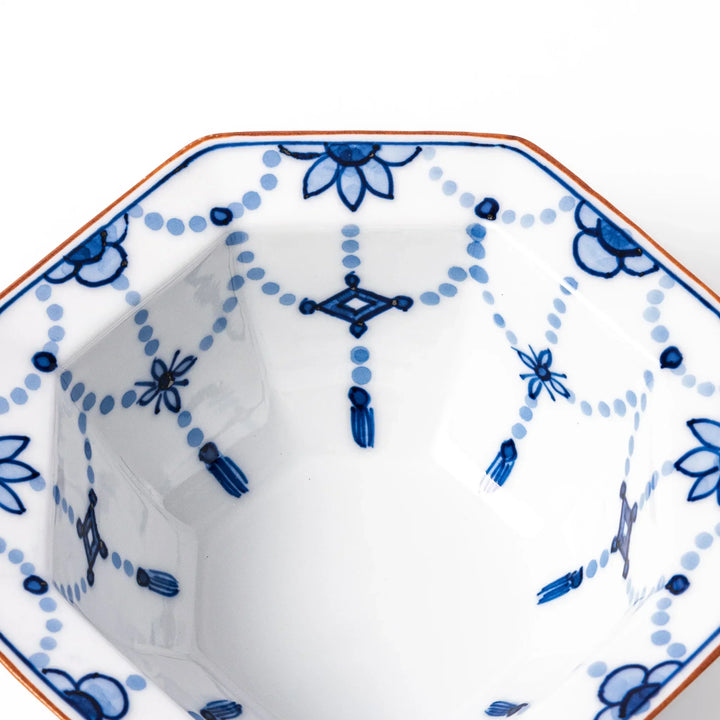 White octagonal dessert bowl with blue floral garland and red rim featuring fine geometric detailing.