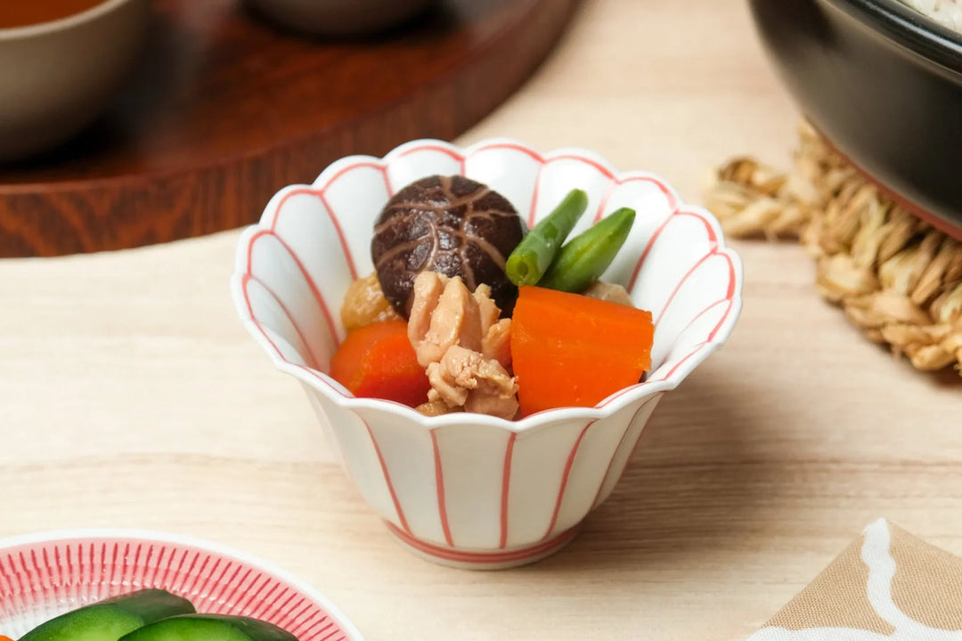 Japanese scalloped bowl with red lines holding simmered vegetables including carrot shiitake and green beans