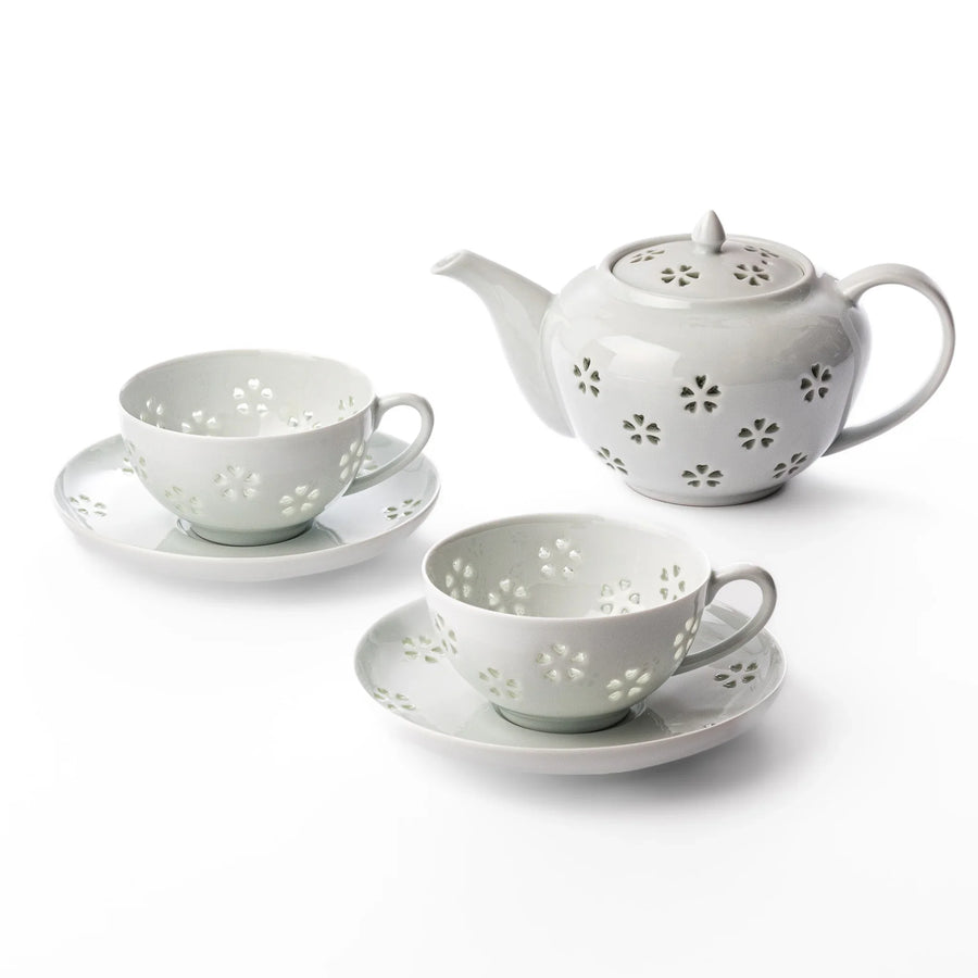 Japanese porcelain tea set with teapot and teacups featuring delicate translucent petal cutout design.