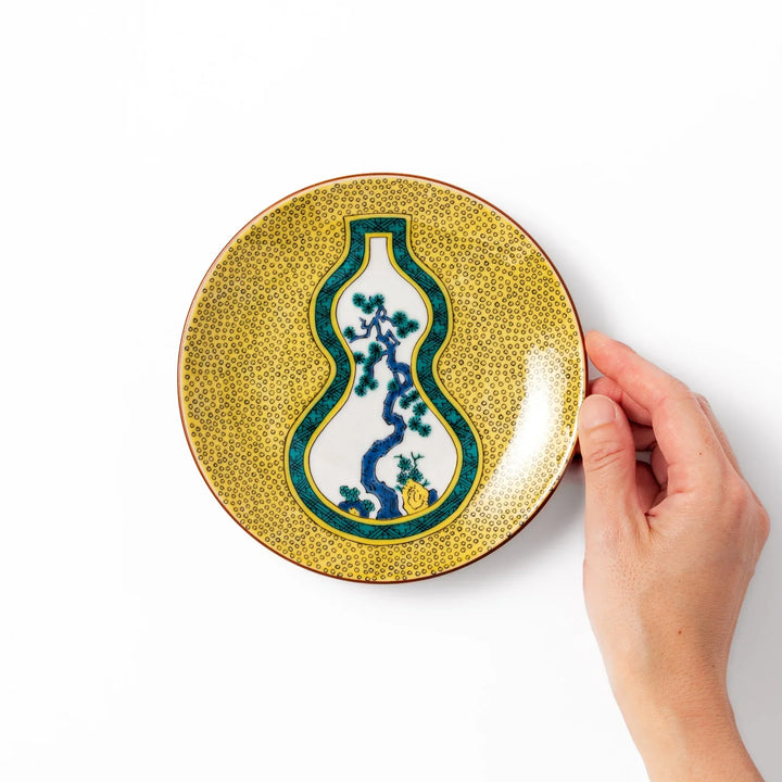 Japanese porcelain dessert plate with yellow patterned background gourd center blue pine and green leaves.