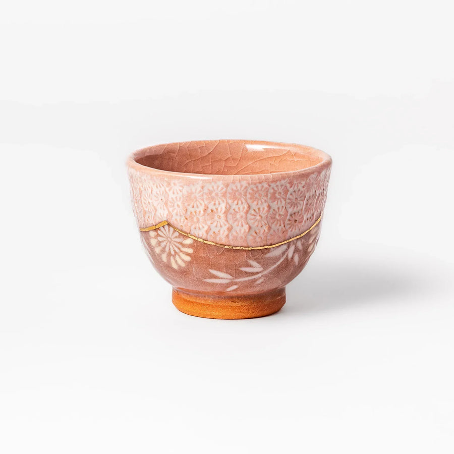 Pink crackle-glazed cup with gold accent and floral design, blending traditional charm and warmth.