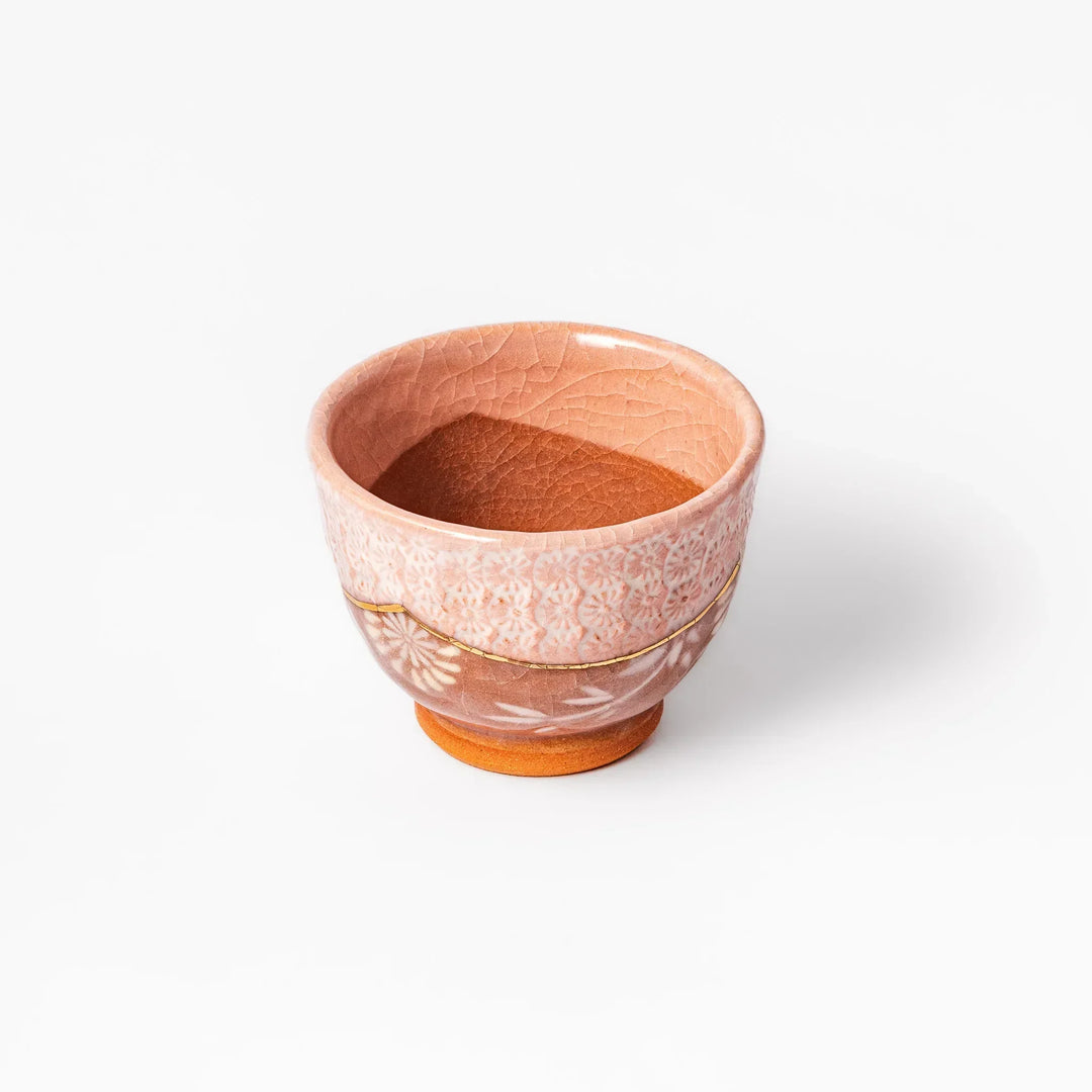Pink crackle-glazed cup with gold accent and floral design, blending traditional charm and warmth.