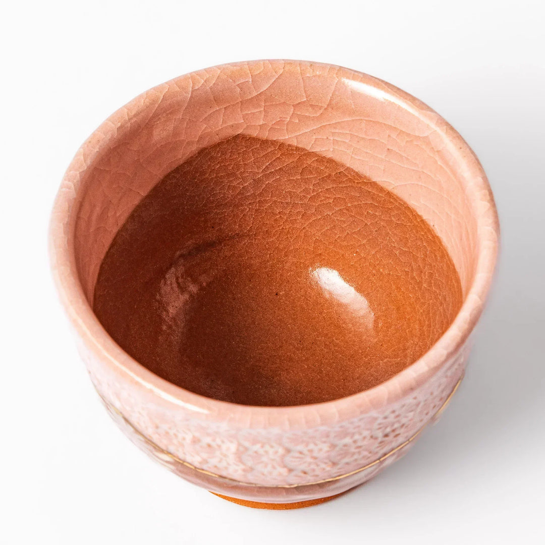 Pink crackle-glazed cup with gold accent and floral design, blending traditional charm and warmth.