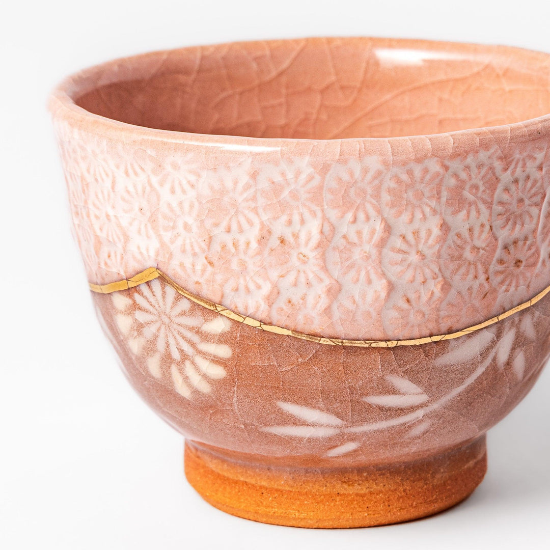 Pink crackle-glazed cup with gold accent and floral design, blending traditional charm and warmth.