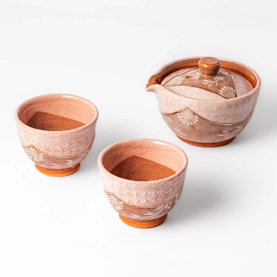Three piece Japanese ceramic tea set with pink crackle glaze floral design teapot and cups with gold accents.