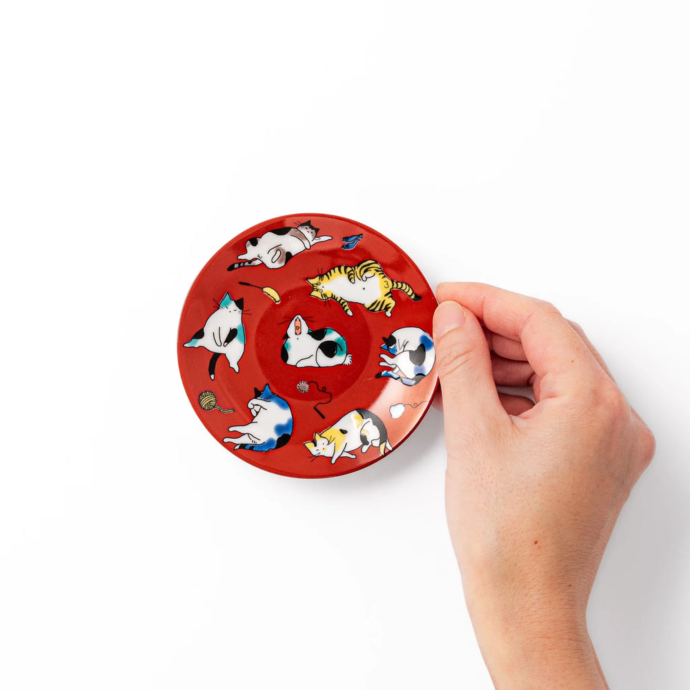 Red Japanese porcelain sauce dish featuring playful cat illustrations in various poses, perfect for soy sauce or dipping.