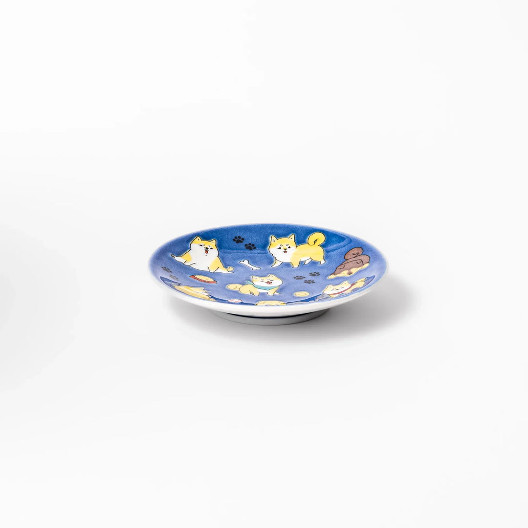 Round Japanese ceramic sauce dish with deep blue background featuring playful Shiba Inu dogs and paw prints.