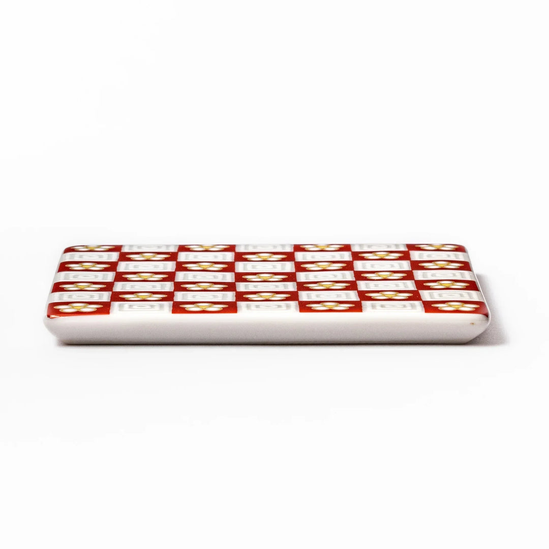 Square Japanese ceramic coaster with red and white checkered pattern and plum blossom motifs for dining.