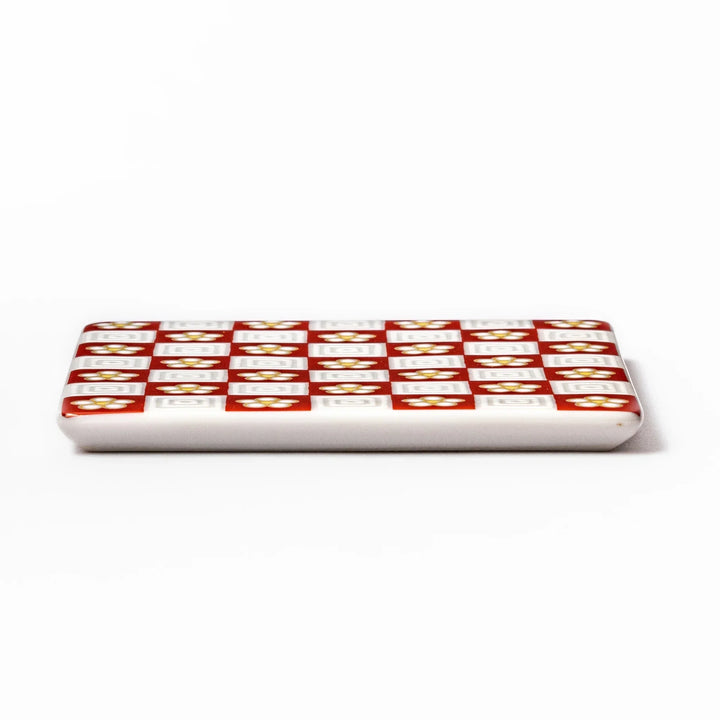 Square Japanese ceramic coaster with red and white checkered pattern and plum blossom motifs for dining.