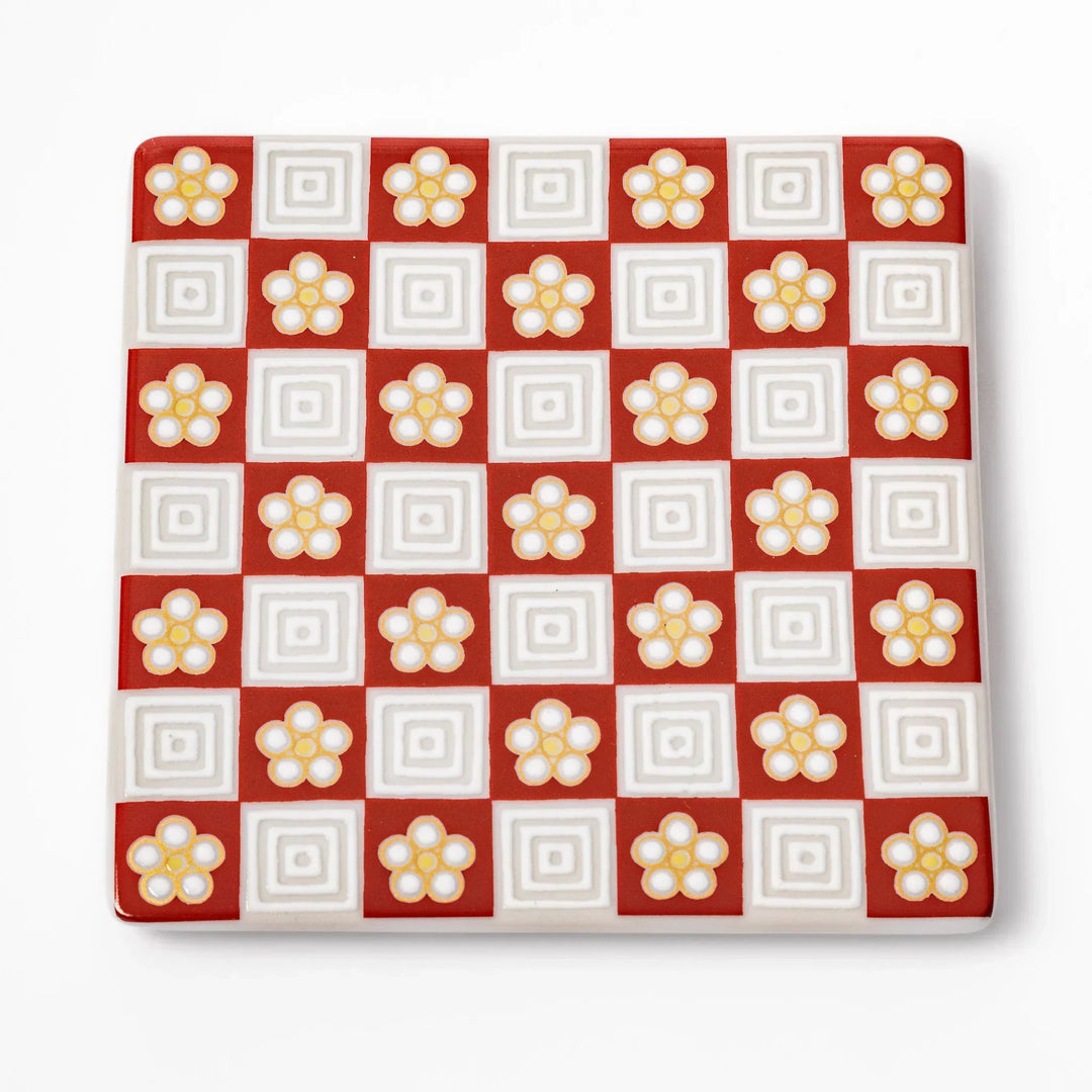 Square Japanese ceramic coaster with red and white checkered pattern and plum blossom motifs for dining.