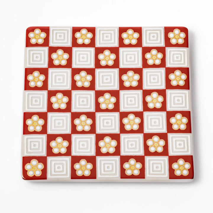 Square Japanese ceramic coaster with red and white checkered pattern and plum blossom motifs for dining.