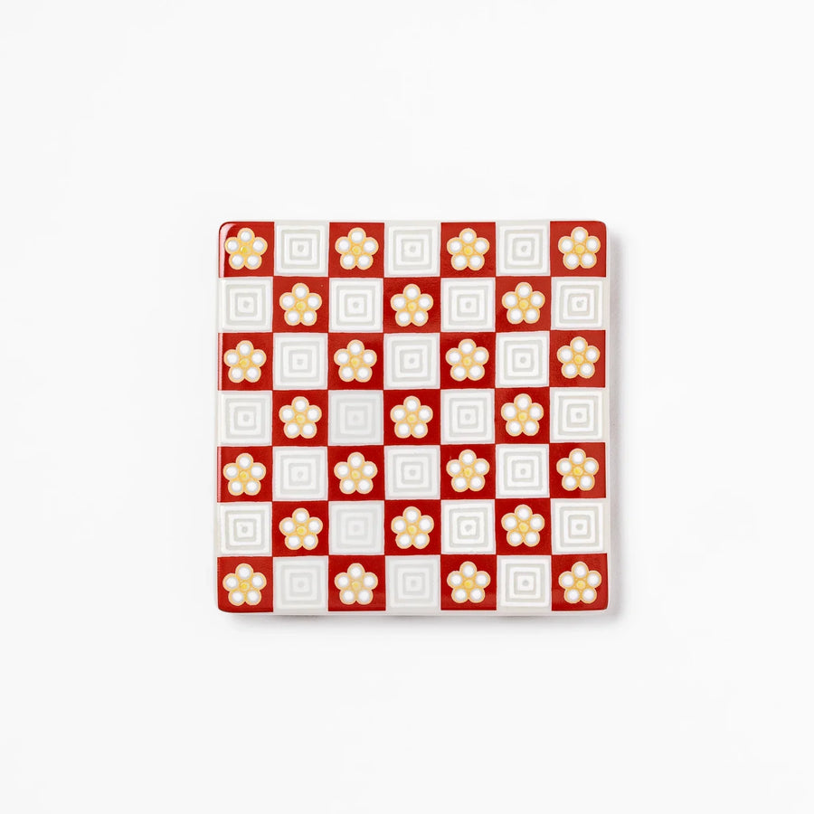 Square Japanese ceramic coaster with red and white checkered pattern and plum blossom motifs for dining.