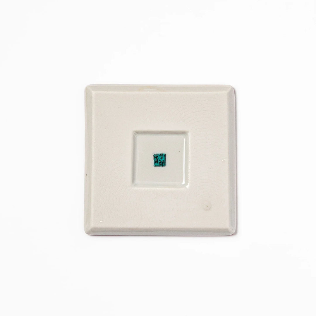 Square Japanese ceramic coaster with red background and plum and chrysanthemum designs for elegant tables.