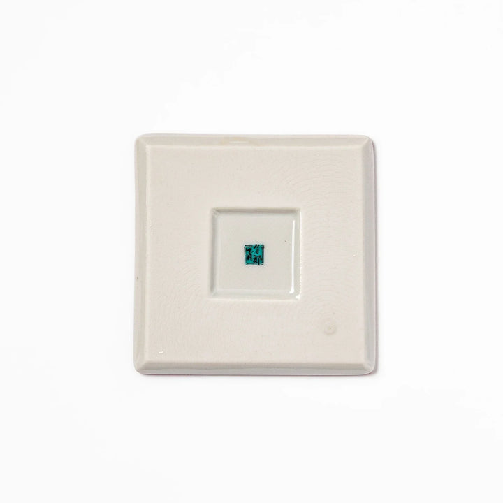 Square Japanese ceramic coaster with red background and plum and chrysanthemum designs for elegant tables.