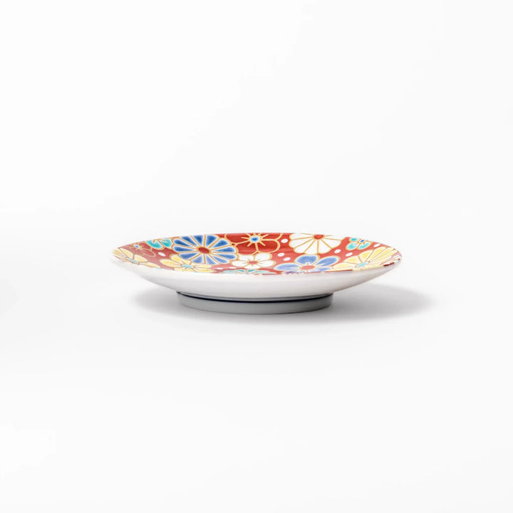 Round Japanese ceramic sauce dish with red background and plum and chrysanthemum motifs for condiments.