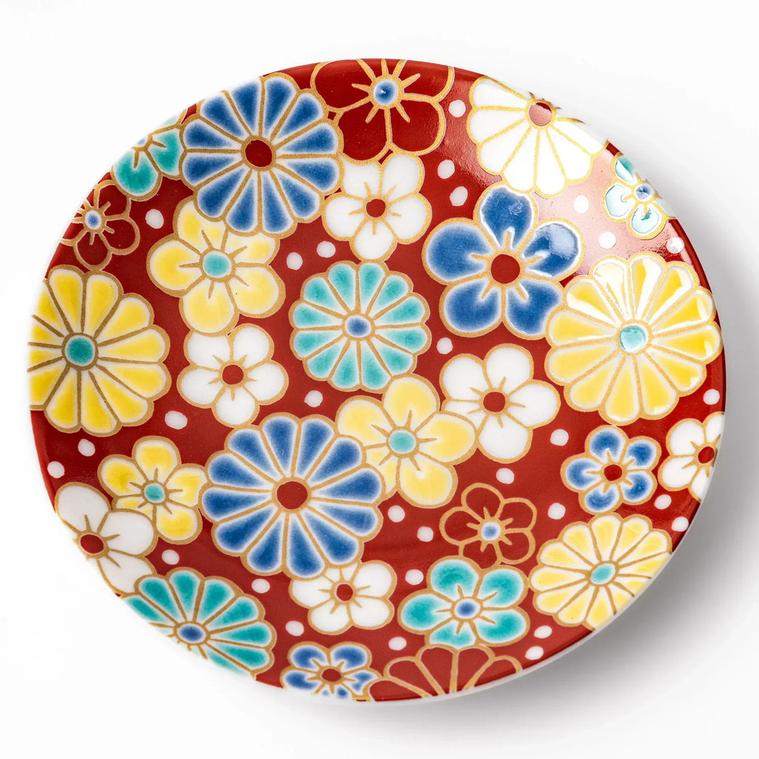 Round Japanese ceramic sauce dish with red background and plum and chrysanthemum motifs for condiments.