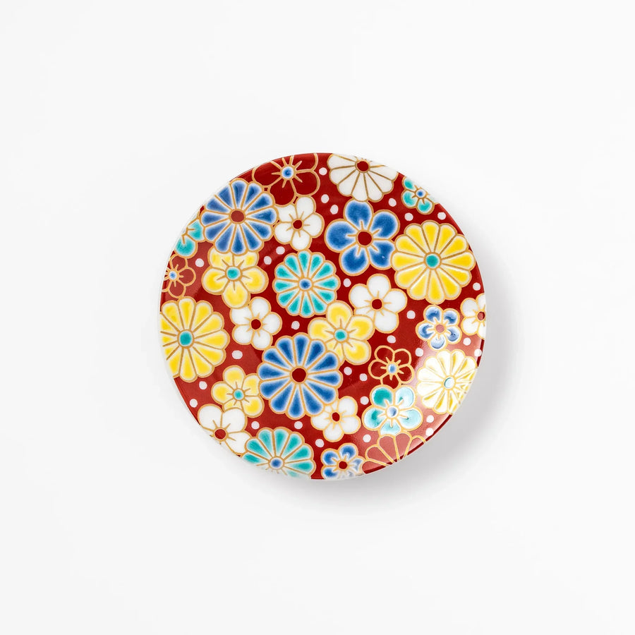 Round Japanese ceramic sauce dish with red background and plum and chrysanthemum motifs for condiments.