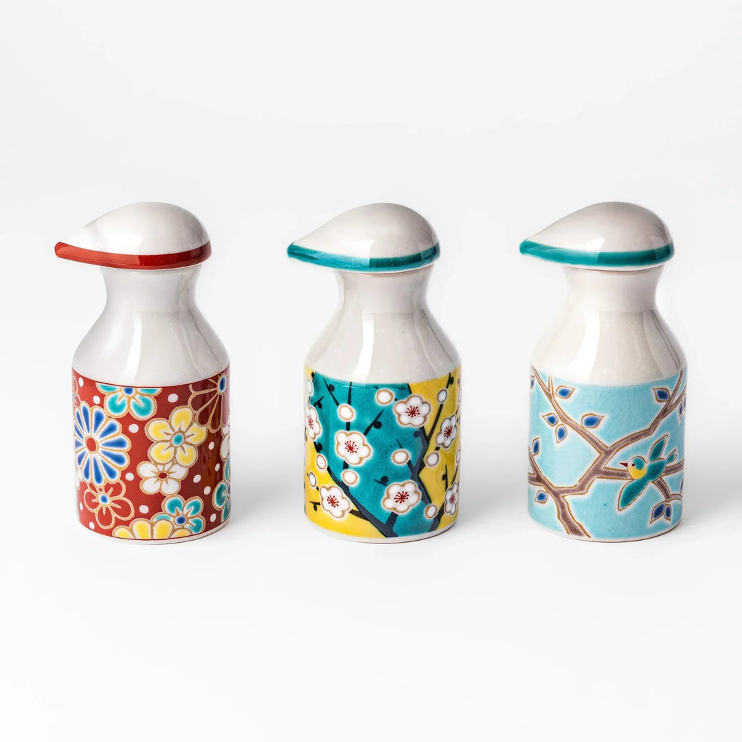 Set of Japanese porcelain soy sauce dispensers with floral and bird motifs in red, yellow, and blue, handcrafted design.