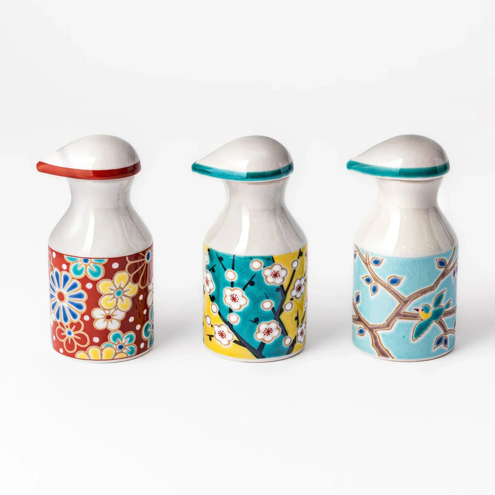 Set of Japanese porcelain soy sauce dispensers with floral and bird motifs in red, yellow, and blue, handcrafted design.