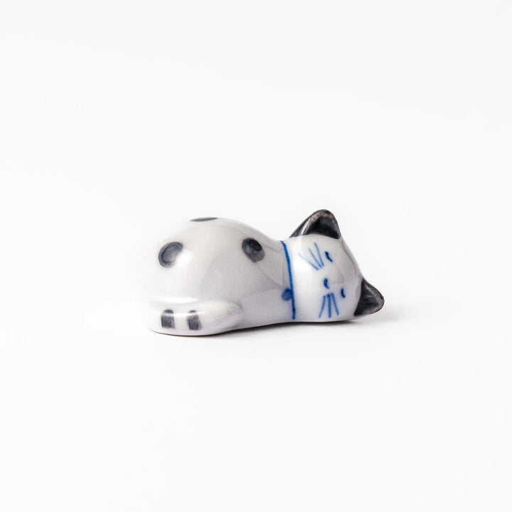 White ceramic cat chopstick rest with green dots in sleeping pose bringing natural charm to table.