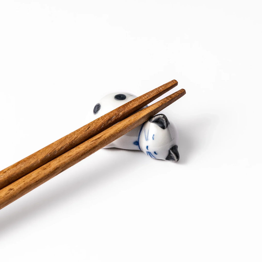 White ceramic cat chopstick rest with green dots in sleeping pose bringing natural charm to table.
