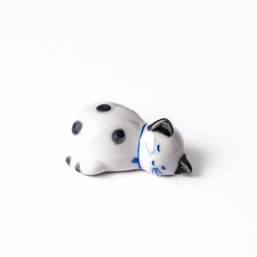 White ceramic cat chopstick rest with green dots in sleeping pose bringing natural charm to table.