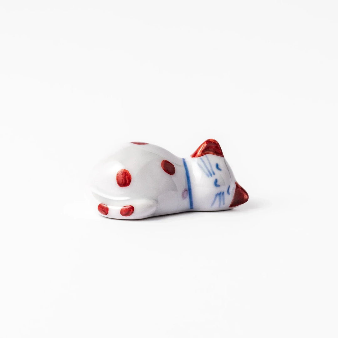 Red polka dot ceramic cat chopstick rest in sleeping pose with hand painted details and glossy finish.