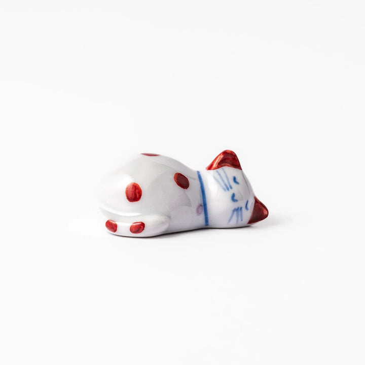 Red polka dot ceramic cat chopstick rest in sleeping pose with hand painted details and glossy finish.
