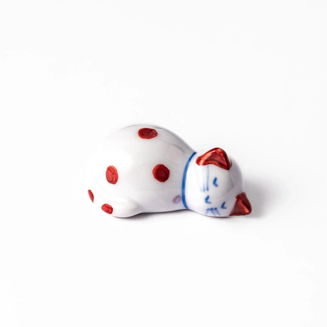 Red polka dot ceramic cat chopstick rest in sleeping pose with hand painted details and glossy finish.
