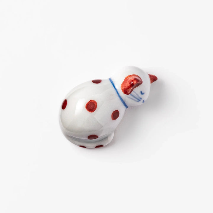 Red polka dot ceramic cat chopstick rest in sleeping pose with hand painted details and glossy finish.