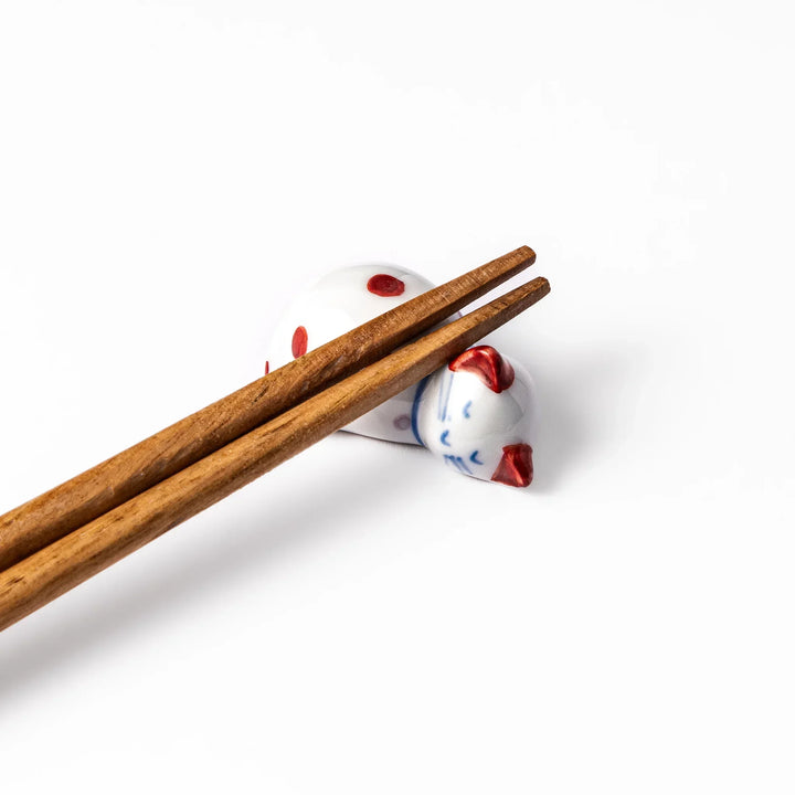 Red polka dot ceramic cat chopstick rest in sleeping pose with hand painted details and glossy finish.