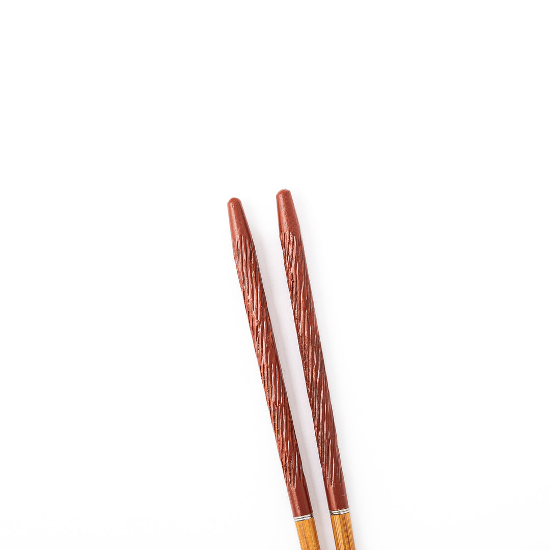 Portable Japanese travel chopsticks featuring a reddish brown textured handle with detailed carvings and a natural wood tip