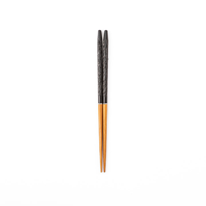Portable Japanese travel chopsticks featuring a black textured handle with detailed carvings and a natural wood tip