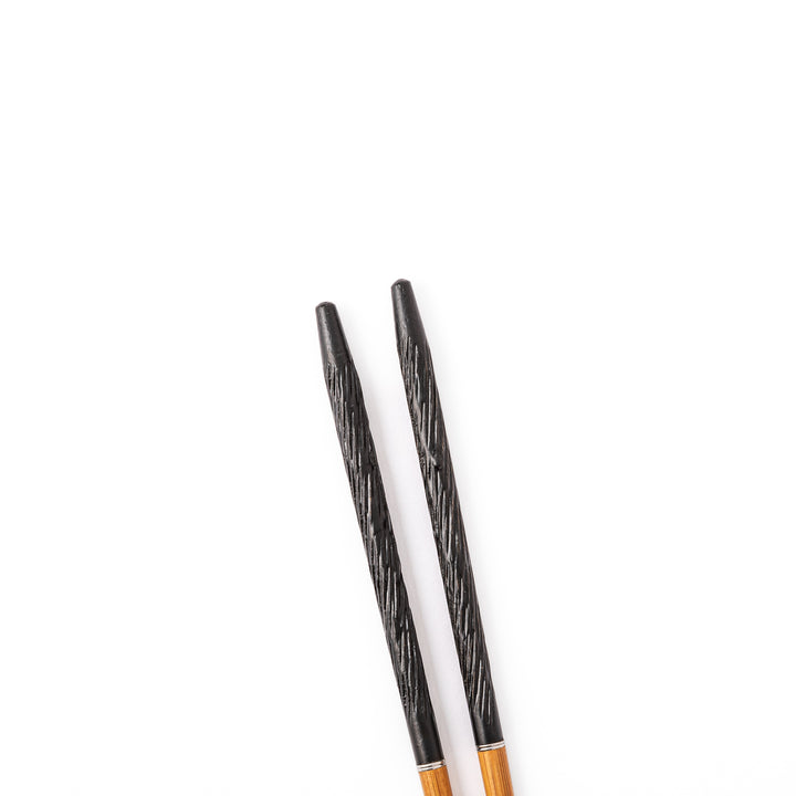 Portable Japanese travel chopsticks featuring a black textured handle with detailed carvings and a natural wood tip