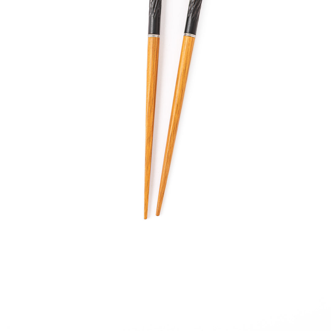 Portable Japanese travel chopsticks featuring a black textured handle with detailed carvings and a natural wood tip