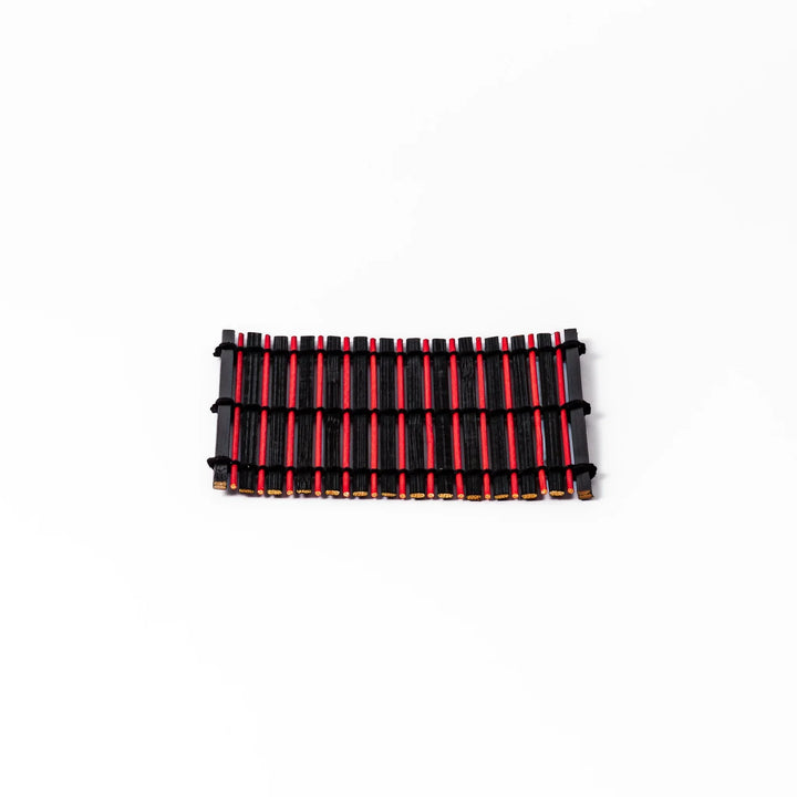 Red and black bamboo coaster with slim vertical slats and black cords for striking Japanese drink setting.