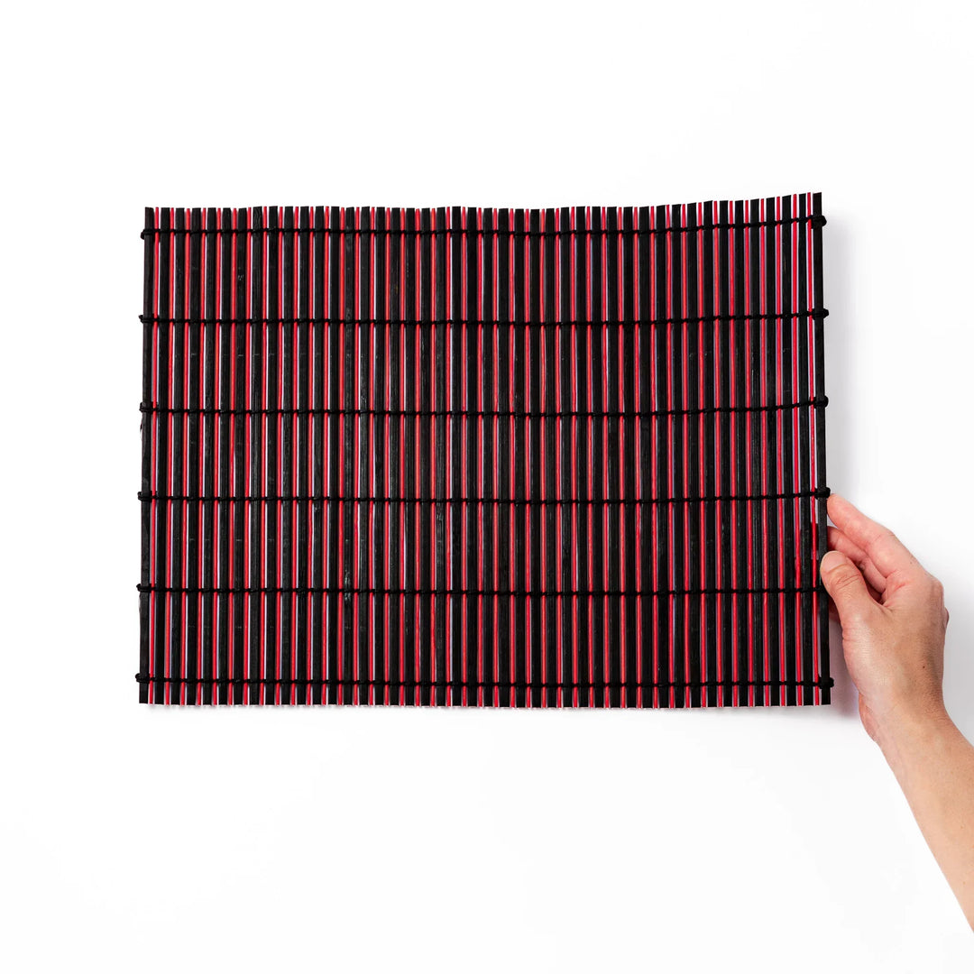 Red and black bamboo table mat with tight slats and black cords for bold modern Japanese table setting.