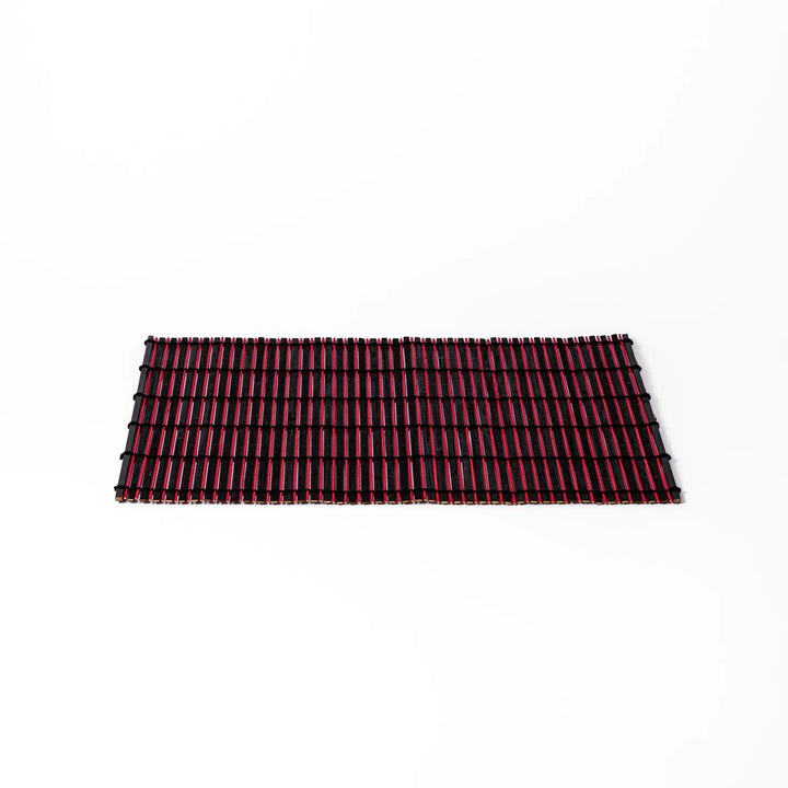 Red and black bamboo table mat with tight slats and black cords for bold modern Japanese table setting.