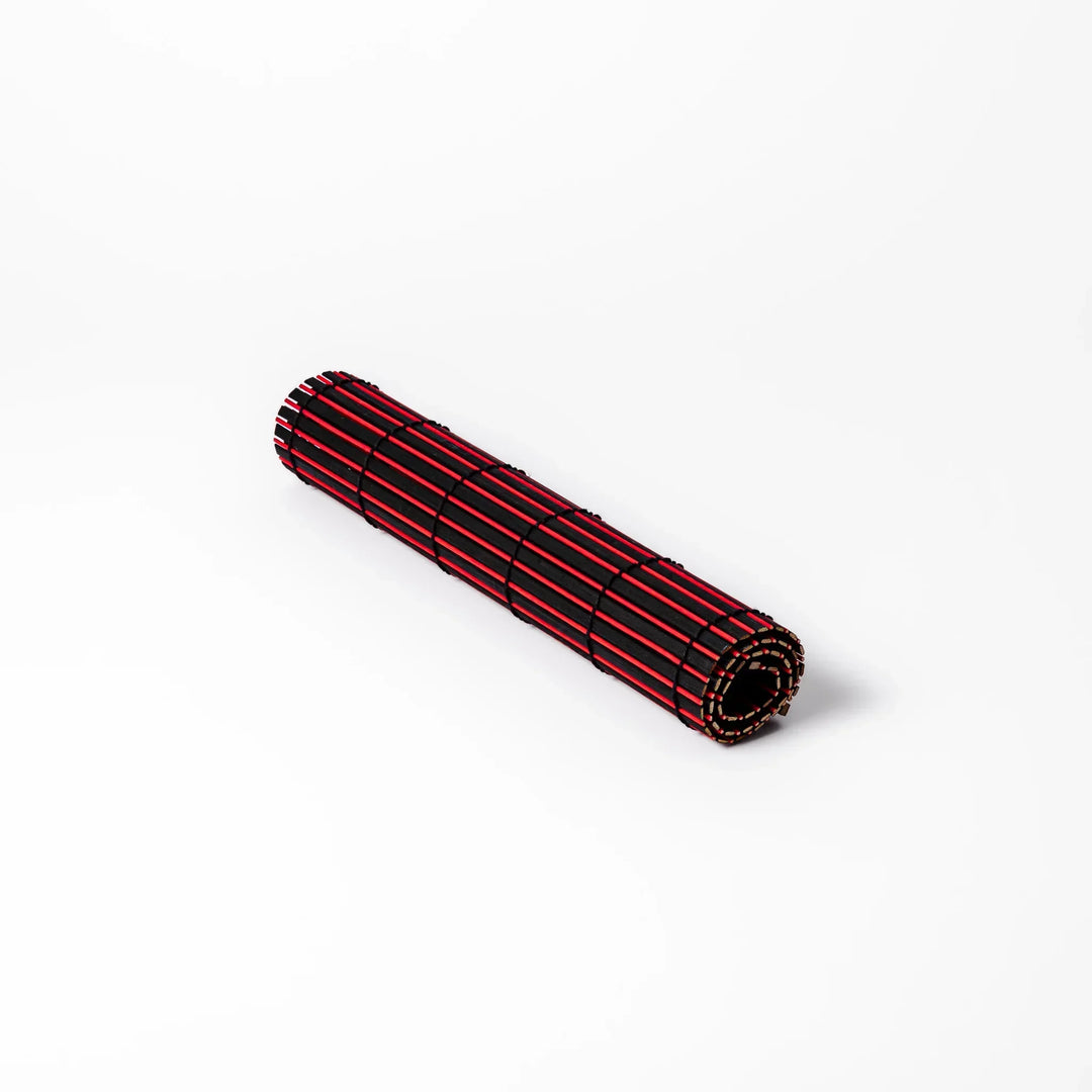 Red and black bamboo table mat with tight slats and black cords for bold modern Japanese table setting.