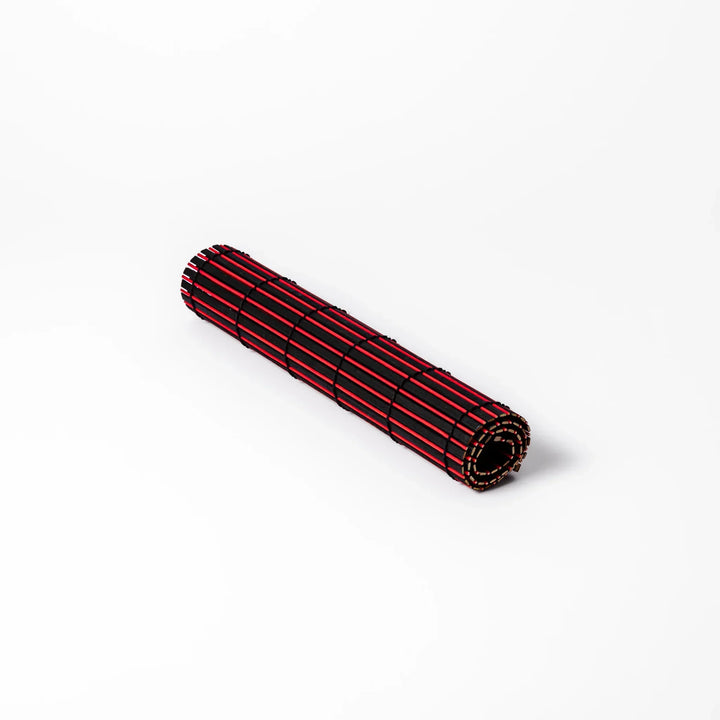 Red and black bamboo table mat with tight slats and black cords for bold modern Japanese table setting.