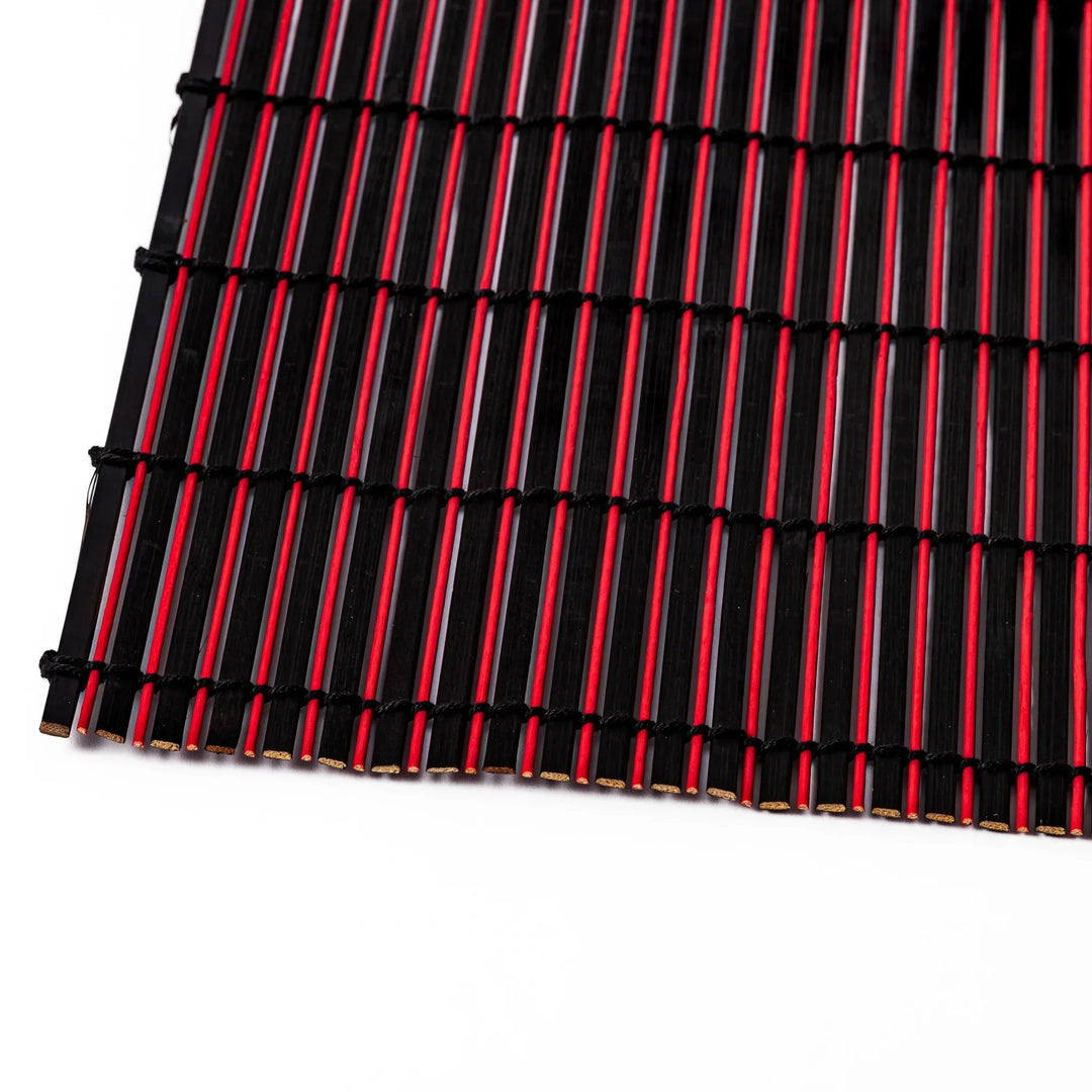 Red and black bamboo table mat with tight slats and black cords for bold modern Japanese table setting.