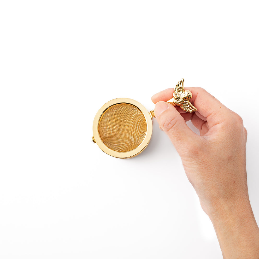 Elegant Japanese rotating gold angel tea strainer with stainless steel mesh basket and drip catcher base