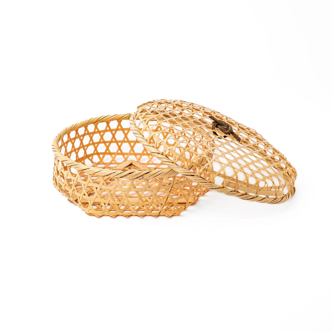 An open round handwoven bamboo serving basket with its hexagonal mesh pattern lid leaning slightly to the side