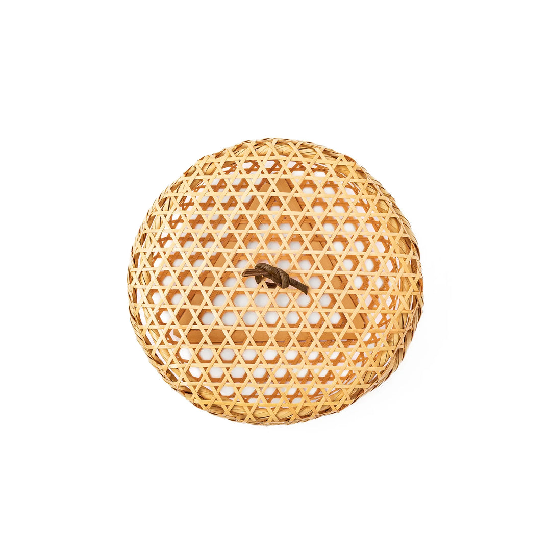 A closed round handwoven bamboo serving basket featuring a decorative brown knotted cord handle on top of the lid