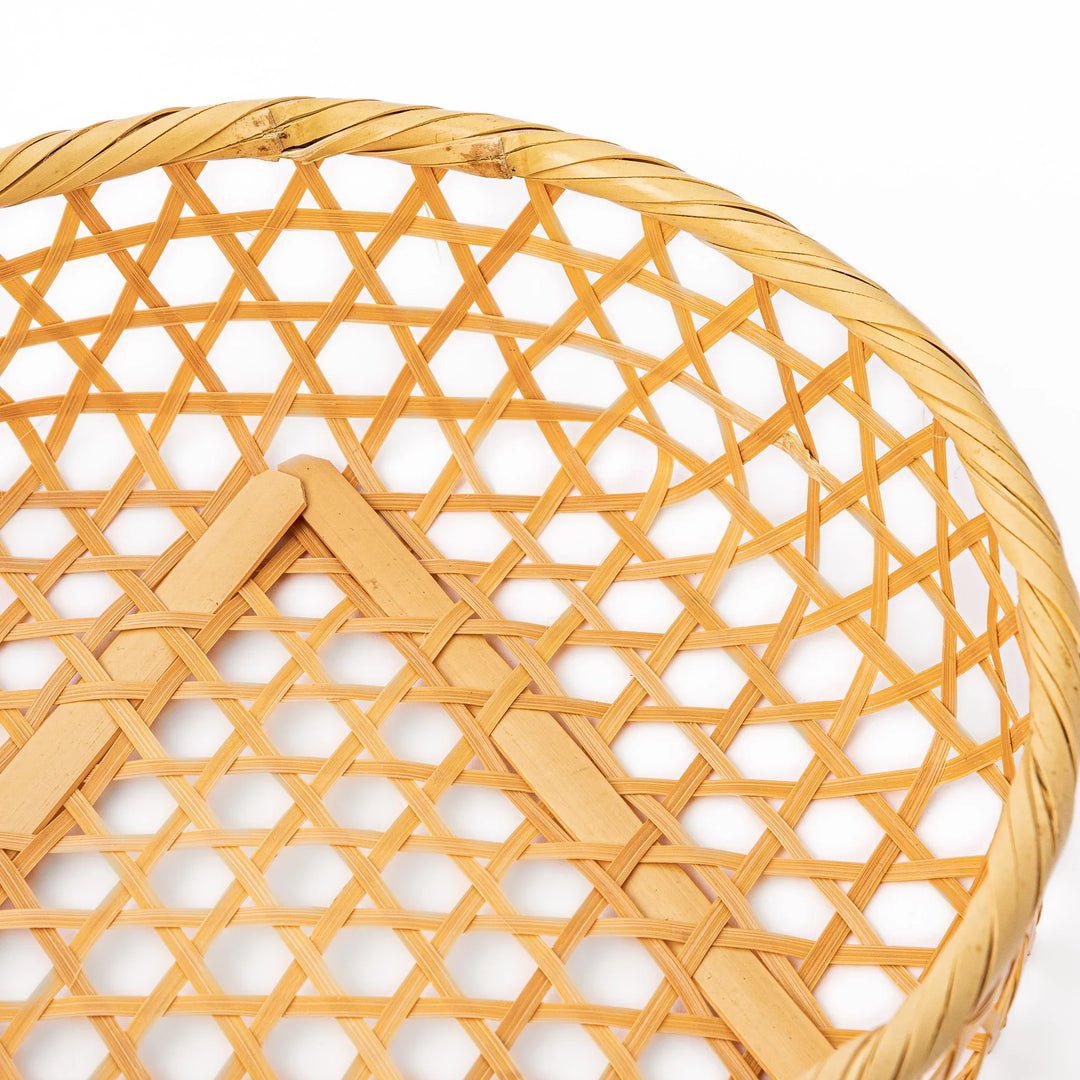 An open round handwoven bamboo serving basket with its hexagonal mesh pattern lid leaning slightly to the side