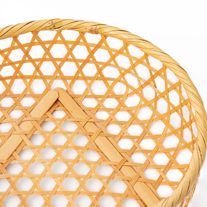 An open round handwoven bamboo serving basket with its hexagonal mesh pattern lid leaning slightly to the side