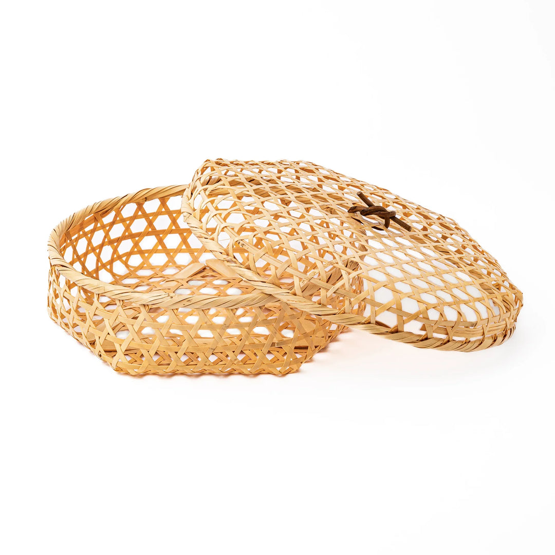 A medium round handwoven bamboo serving basket with a hexagonal mesh pattern lid resting on the woven border