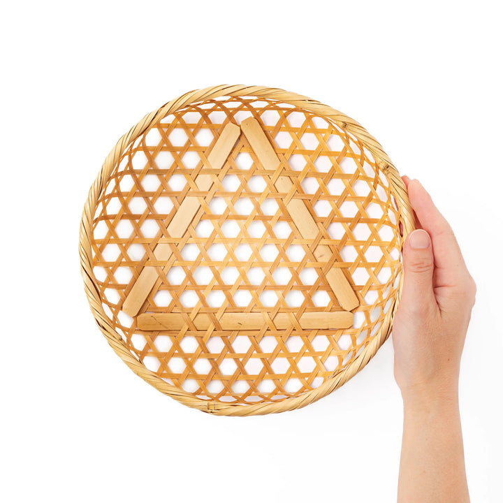 A medium round handwoven bamboo serving basket with a hexagonal mesh pattern lid resting on the woven border