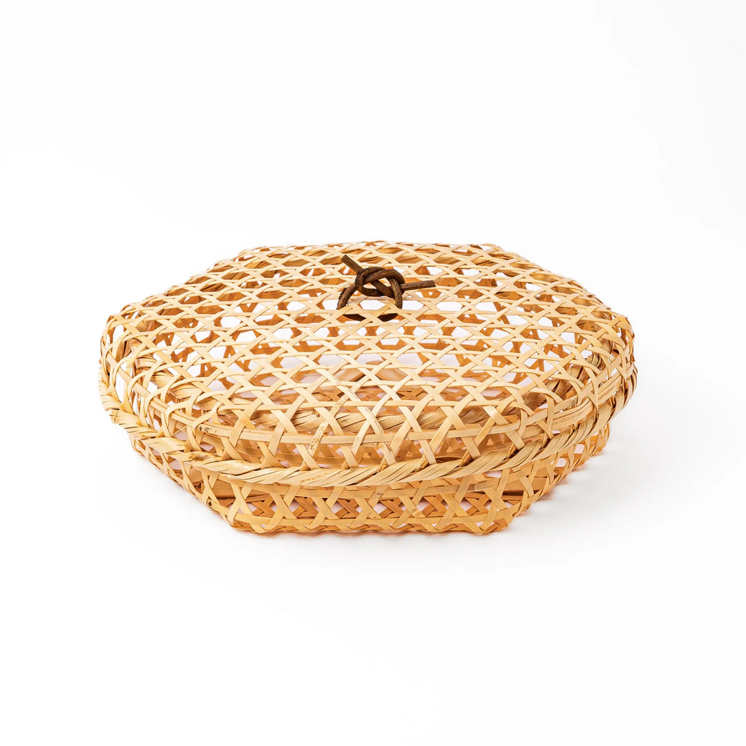 A medium round handwoven bamboo serving basket with a hexagonal mesh pattern lid resting on the woven border