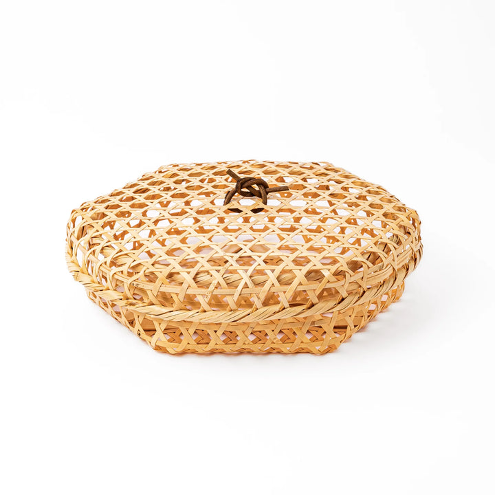A medium round handwoven bamboo serving basket with a hexagonal mesh pattern lid resting on the woven border